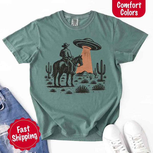 Retro cowboy and horse graphic with UFO beaming light in desert landscape with cacti – western alien mashup design