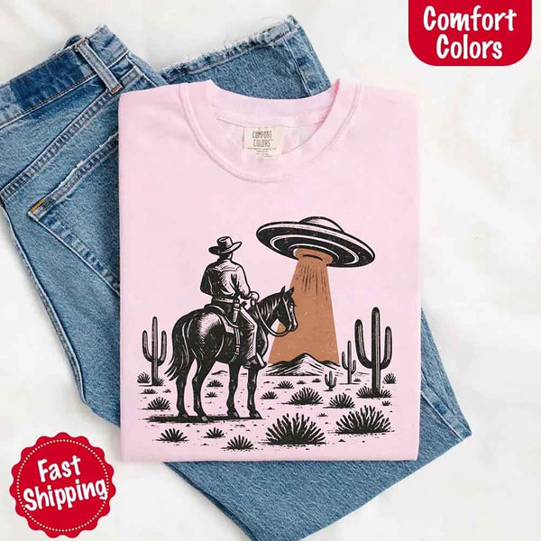 Retro cowboy and horse graphic with UFO beaming light in desert landscape with cacti – western alien mashup design