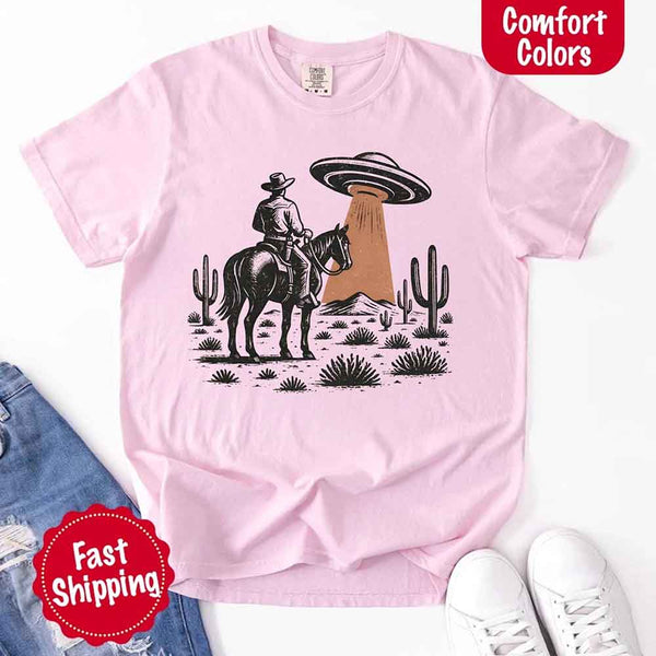 Retro cowboy and horse graphic with UFO beaming light in desert landscape with cacti – western alien mashup design