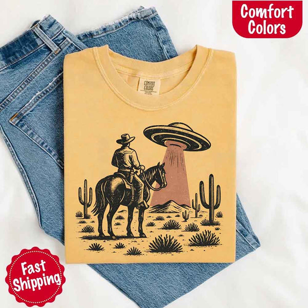 Retro cowboy and horse graphic with UFO beaming light in desert landscape with cacti – western alien mashup design