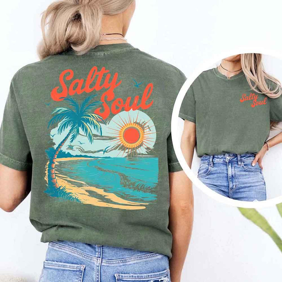 May include a short-sleeve t-shirt with “Salty Soul” printed in bold script on the front left chest and a large back graphic featuring a tropical beach scene with a palm tree, ocean waves, a bright orange sun, and flying birds.