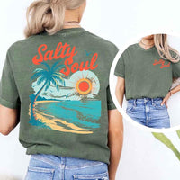 May include a short-sleeve t-shirt with “Salty Soul” printed in bold script on the front left chest and a large back graphic featuring a tropical beach scene with a palm tree, ocean waves, a bright orange sun, and flying birds.