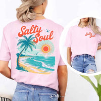 May include a short-sleeve t-shirt with “Salty Soul” printed in bold script on the front left chest and a large back graphic featuring a tropical beach scene with a palm tree, ocean waves, a bright orange sun, and flying birds.