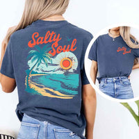 May include a short-sleeve t-shirt with “Salty Soul” printed in bold script on the front left chest and a large back graphic featuring a tropical beach scene with a palm tree, ocean waves, a bright orange sun, and flying birds.