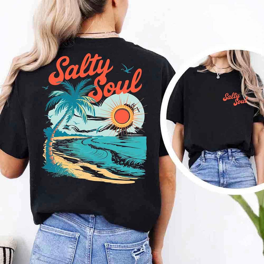 May include a short-sleeve t-shirt with “Salty Soul” printed in bold script on the front left chest and a large back graphic featuring a tropical beach scene with a palm tree, ocean waves, a bright orange sun, and flying birds.