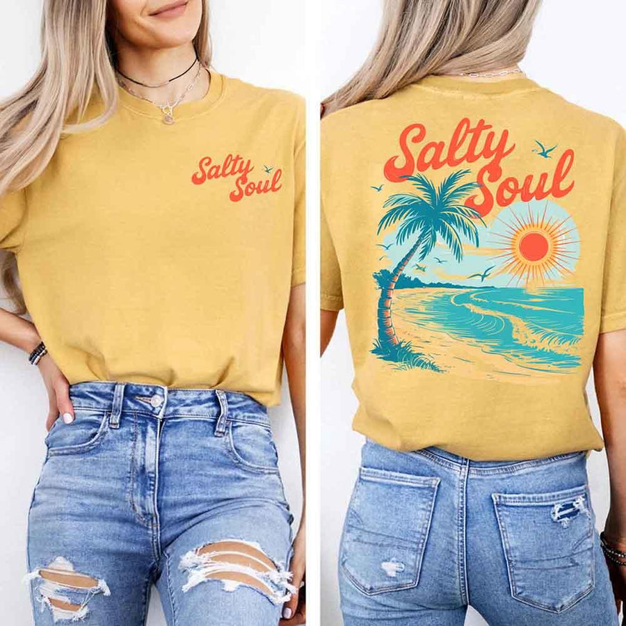 May include a short-sleeve t-shirt with “Salty Soul” printed in bold script on the front left chest and a large back graphic featuring a tropical beach scene with a palm tree, ocean waves, a bright orange sun, and flying birds.