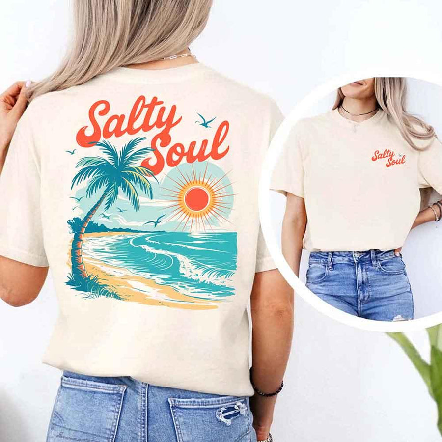 May include a short-sleeve t-shirt with “Salty Soul” printed in bold script on the front left chest and a large back graphic featuring a tropical beach scene with a palm tree, ocean waves, a bright orange sun, and flying birds.