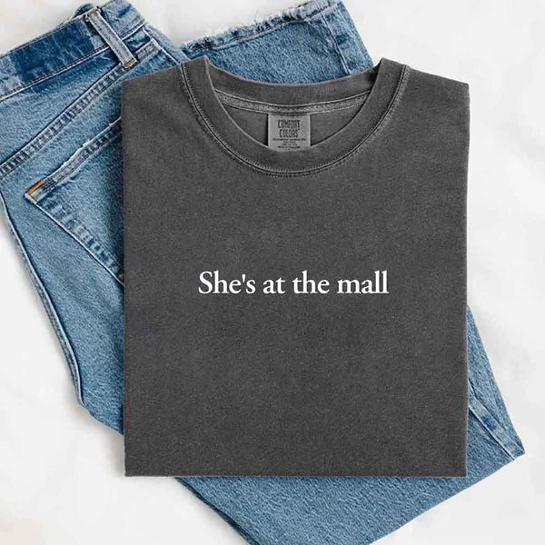 May include a folded Pepper Comfort Colors T-shirt with the text "She's at the mall" printed in white, styled with denim jeans and white sneakers, promoting fast shipping