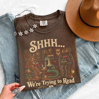 May include a Shhh We're Trying to Read Comfort Colors T-Shirt featuring a playful book lover statement design.