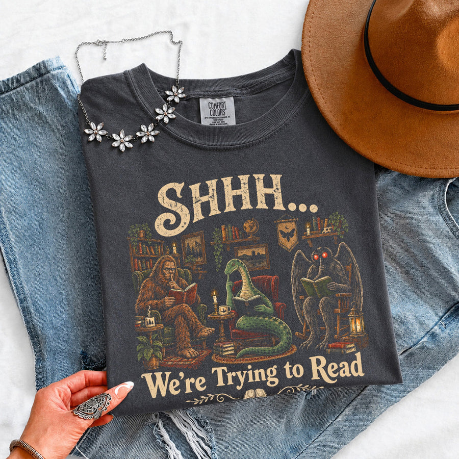 May include a Shhh We're Trying to Read Comfort Colors T-Shirt featuring a playful book lover statement design.