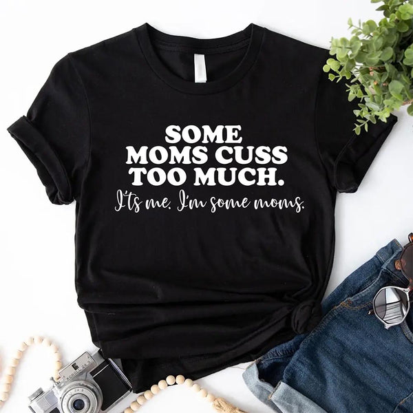 Black t-shirt with humorous text Some moms cuss too much on a white surface with accessories.