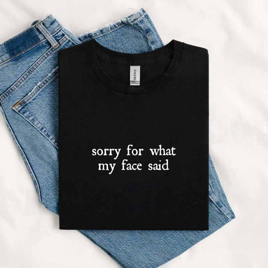 folded black t-shirt funny graphic t-shirt reading “Sorry for What My Face Said”.