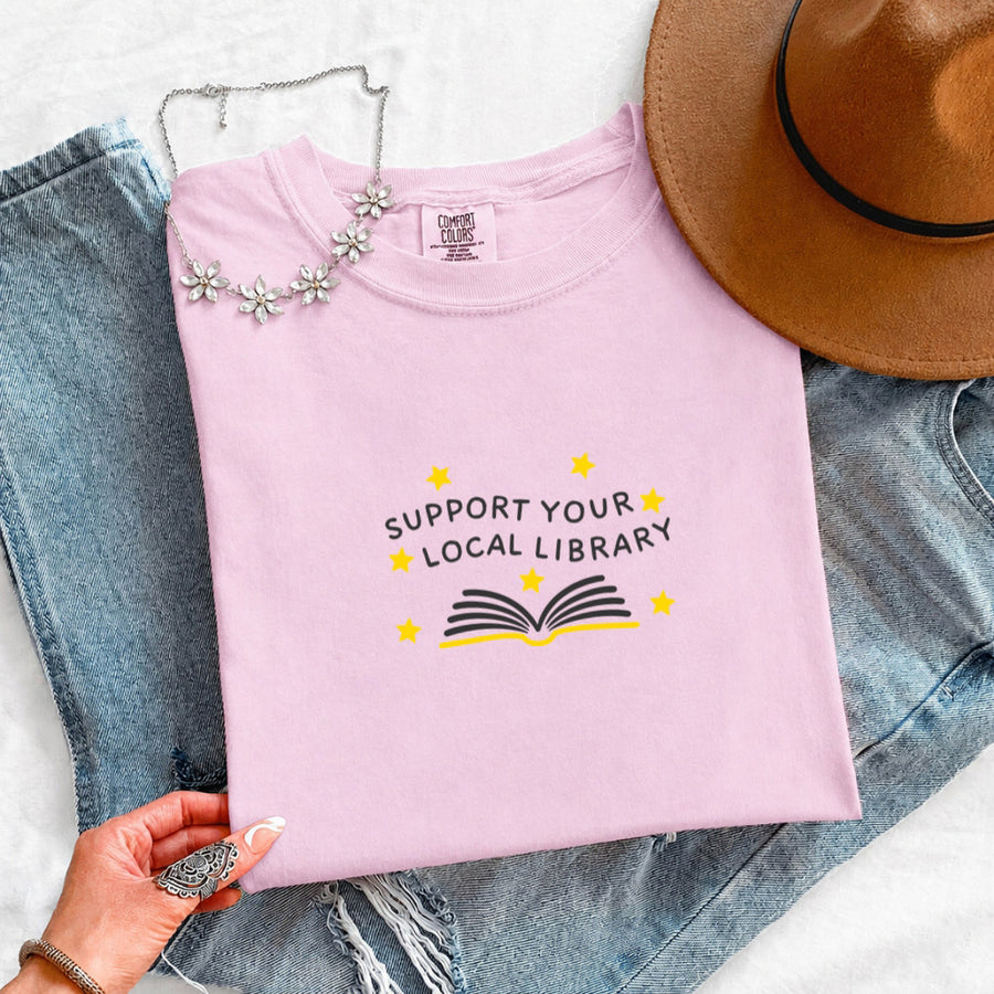 May include a Support Your Local Library Comfort Colors T-Shirt featuring a simple library-inspired statement design.