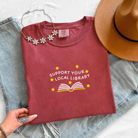 May include a Support Your Local Library Comfort Colors T-Shirt featuring a simple library-inspired statement design.