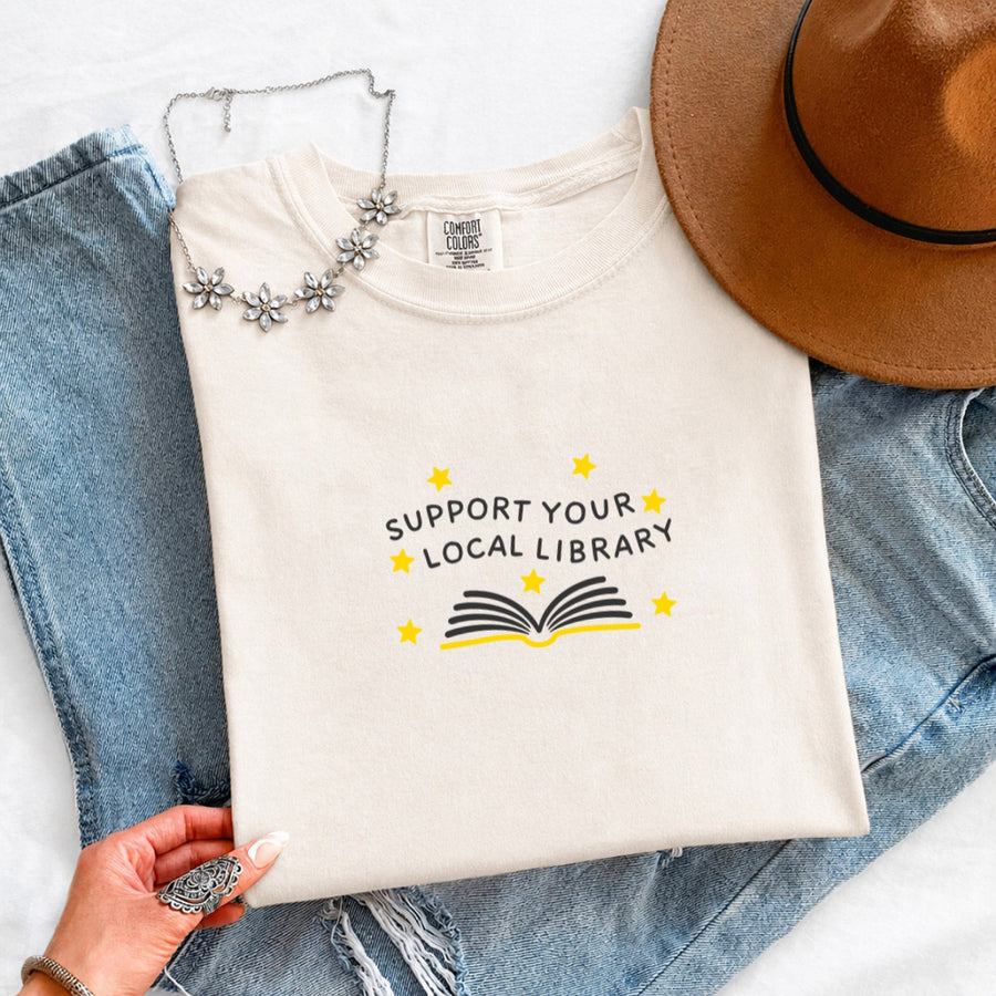 May include a Support Your Local Library Comfort Colors T-Shirt featuring a simple library-inspired statement design.
