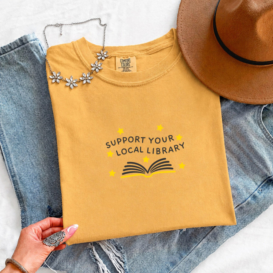 May include a Support Your Local Library Comfort Colors T-Shirt featuring a simple library-inspired statement design.