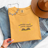 May include a Support Your Local Library Comfort Colors T-Shirt featuring a simple library-inspired statement design.