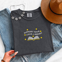 May include a Support Your Local Library Comfort Colors T-Shirt featuring a simple library-inspired statement design.