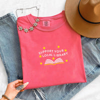 May include a Support Your Local Library Comfort Colors T-Shirt featuring a simple library-inspired statement design.