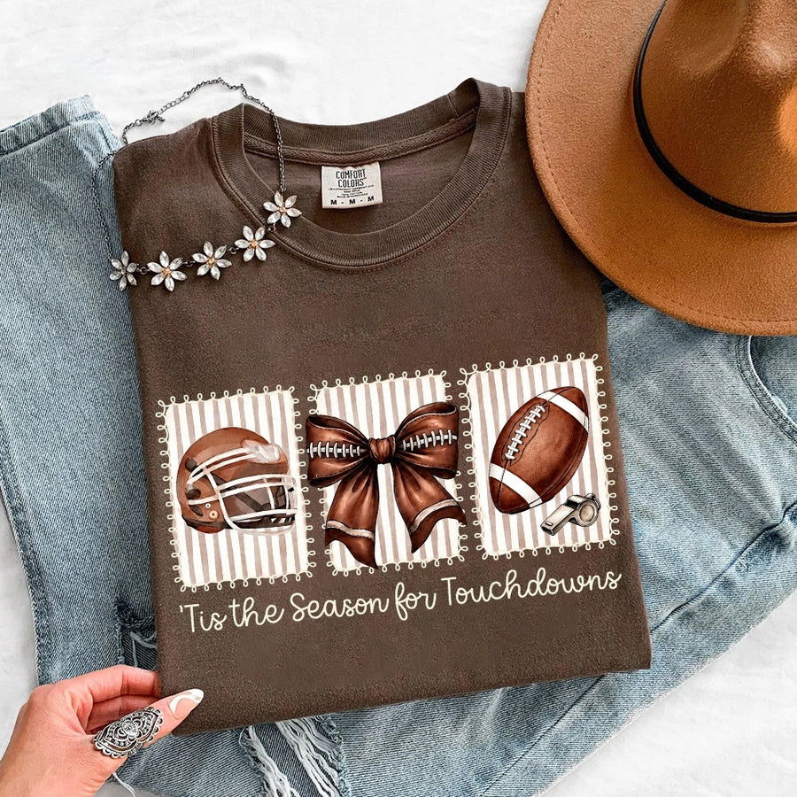May include a Comfort Colors T-shirt featuring a 'Tis the Season for Touchdowns football-inspired design, perfect for football fans, game days, tailgates, and holiday gatherings.