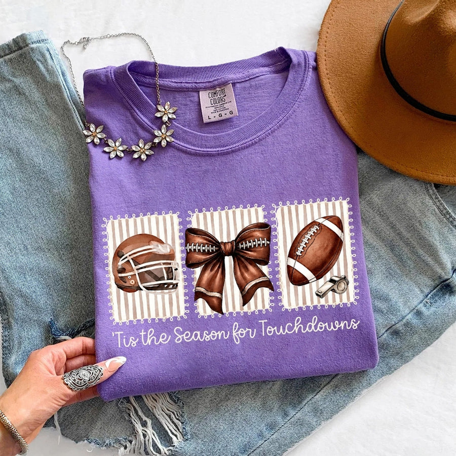 May include a Comfort Colors T-shirt featuring a 'Tis the Season for Touchdowns football-inspired design, perfect for football fans, game days, tailgates, and holiday gatherings.