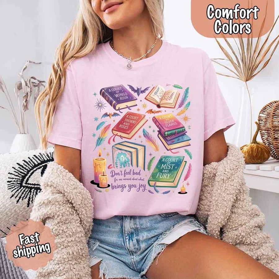 May include colorful illustrated books from the “A Court of Thorns and Roses” series surrounded by feathers, candles, and stars, with the quote “Don’t feel bad for one moment about what brings you joy,” celebrating fantasy fiction and book lover pride.
