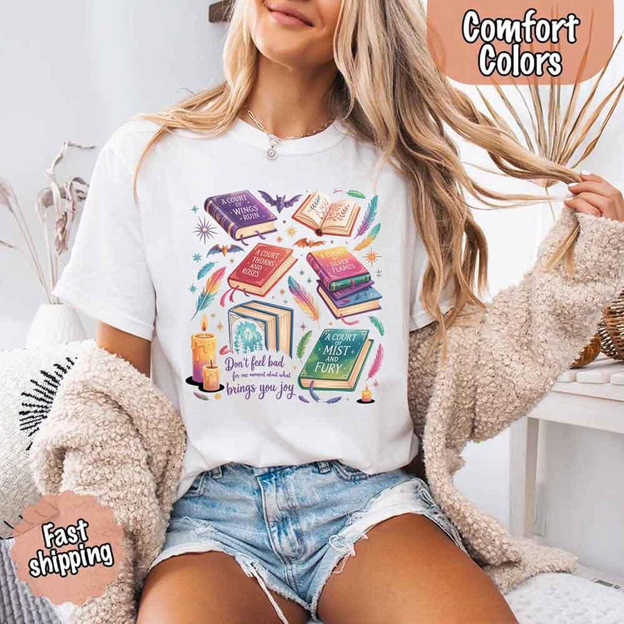 May include colorful illustrated books from the “A Court of Thorns and Roses” series surrounded by feathers, candles, and stars, with the quote “Don’t feel bad for one moment about what brings you joy,” celebrating fantasy fiction and book lover pride.