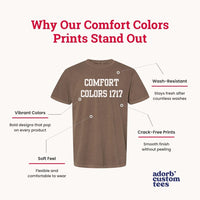 A promotional graphic for Comfort Colors t-shirts on a light beige background. The main subject is a brown short-sleeve t-shirt with 'COMFORT COLORS 1717' printed in white on the chest.