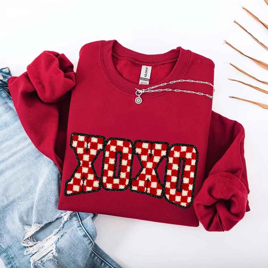 May include a crewneck sweatshirt with an XOXO checkered design featuring a soft, furry-style printed texture.