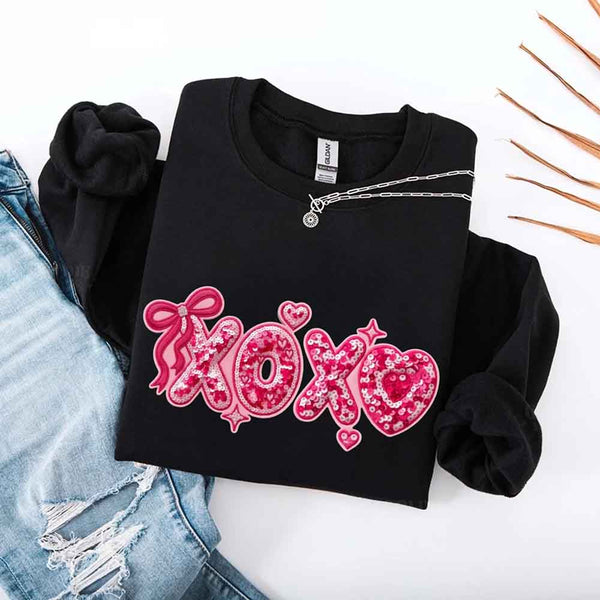May include a crewneck sweatshirt featuring an XOXO design with a faux printed sequin appearance on the front.