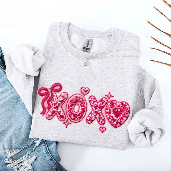 May include a crewneck sweatshirt featuring an XOXO design with a faux printed sequin appearance on the front.