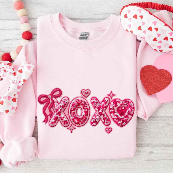 May include a crewneck sweatshirt featuring an XOXO design with a faux printed sequin appearance on the front.