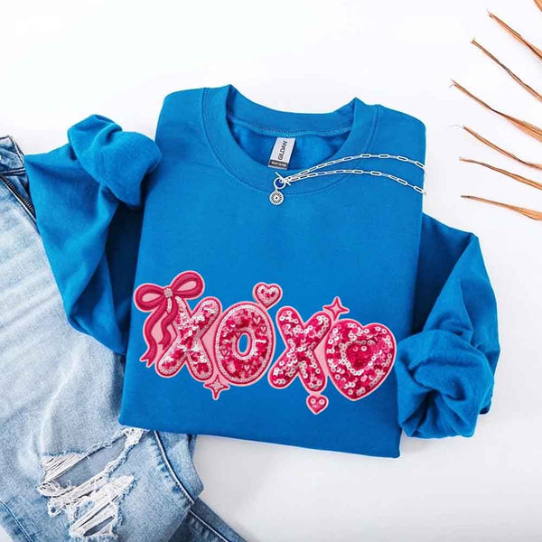 May include a crewneck sweatshirt featuring an XOXO design with a faux printed sequin appearance on the front.