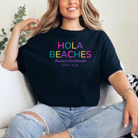 May include Black colorful “Bride Tribe” beach bachelorette T-shirts worn by a group of women, vibrant summer tones, seaside backdrop, fun party vibe, coordinated bridal crew outfits celebrating together!