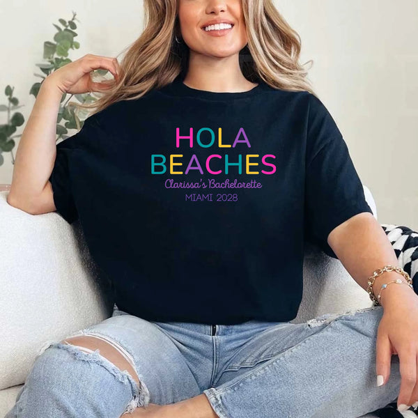 May include Black colorful “Bride Tribe” beach bachelorette T-shirts worn by a group of women, vibrant summer tones, seaside backdrop, fun party vibe, coordinated bridal crew outfits celebrating together!