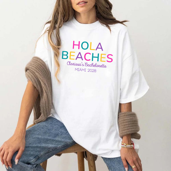 May include White colorful “Bride Tribe” beach bachelorette T-shirts worn by a group of women, vibrant summer tones, seaside backdrop, fun party vibe, coordinated bridal crew outfits celebrating together!