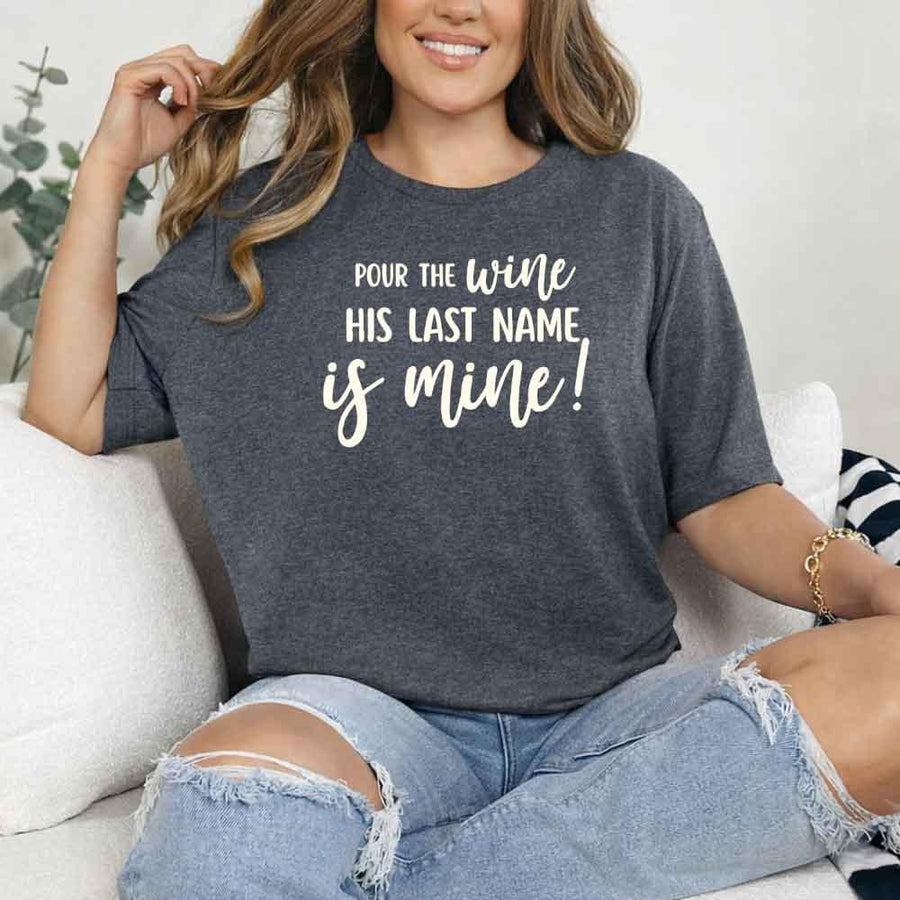 May include Dark Heather Bachelorette Party Shirt with "Pour The Wine His Last Name Is Mine" T-Shirt design, perfect for bridal celebrations, fun nights, and making a statement!
