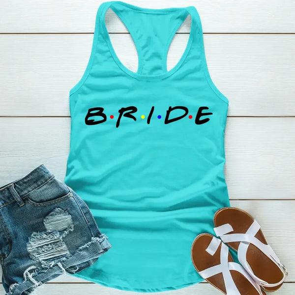 sky blue tank top with the word 'BRIDE' printed in black letters, positioned on a wooden surface with blue denim shorts and white sandals in the background.