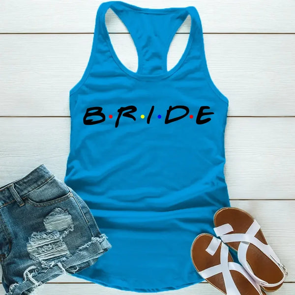 Blue tank top with the word 'BRIDE' printed in black letters, positioned on a wooden surface with blue denim shorts and white sandals in the background.
