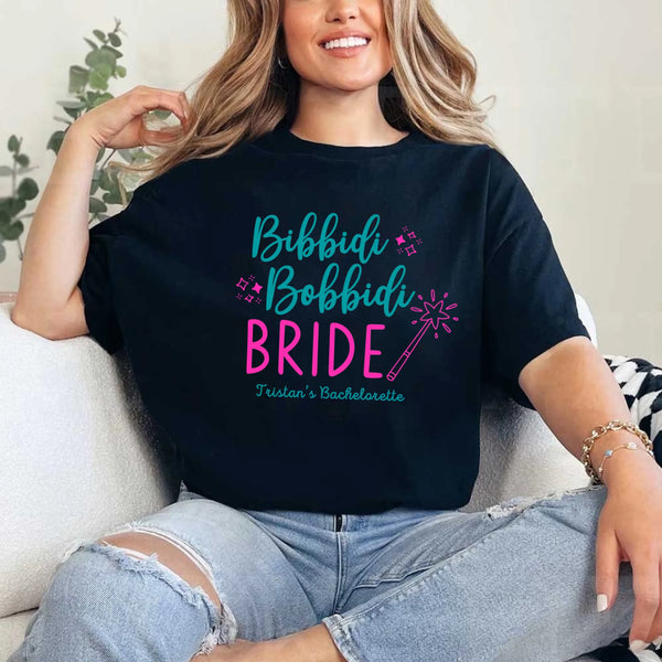 May include Black a personalized Bibbidi Bobbidi Bride T-shirt with fairytale bridal lettering for a bachelorette party or wedding celebration.