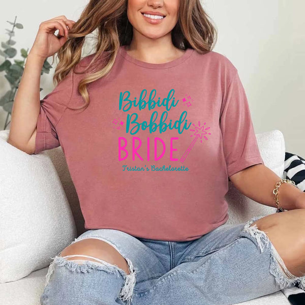 May include Mauve a personalized Bibbidi Bobbidi Bride T-shirt with fairytale bridal lettering for a bachelorette party or wedding celebration.
