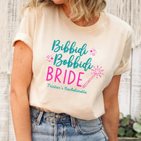 May include Cream a personalized Bibbidi Bobbidi Bride T-shirt with fairytale bridal lettering for a bachelorette party or wedding celebration.