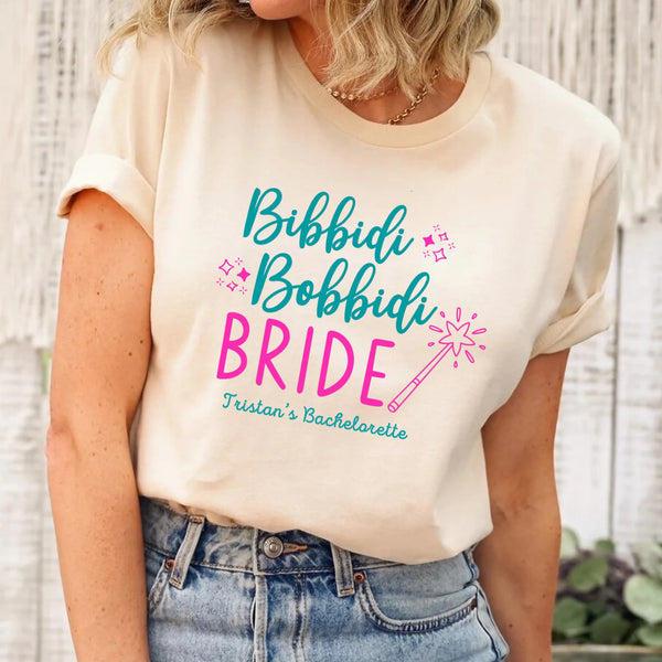 May include Cream a personalized Bibbidi Bobbidi Bride T-shirt with fairytale bridal lettering for a bachelorette party or wedding celebration.