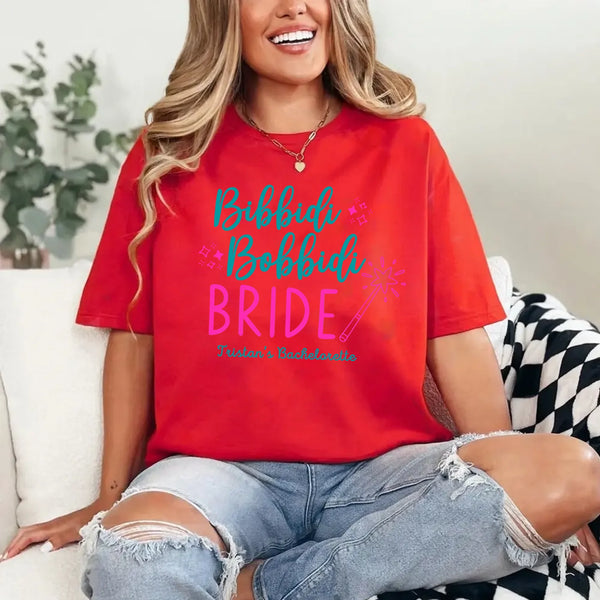 May include Red a personalized Bibbidi Bobbidi Bride T-shirt with fairytale bridal lettering for a bachelorette party or wedding celebration.