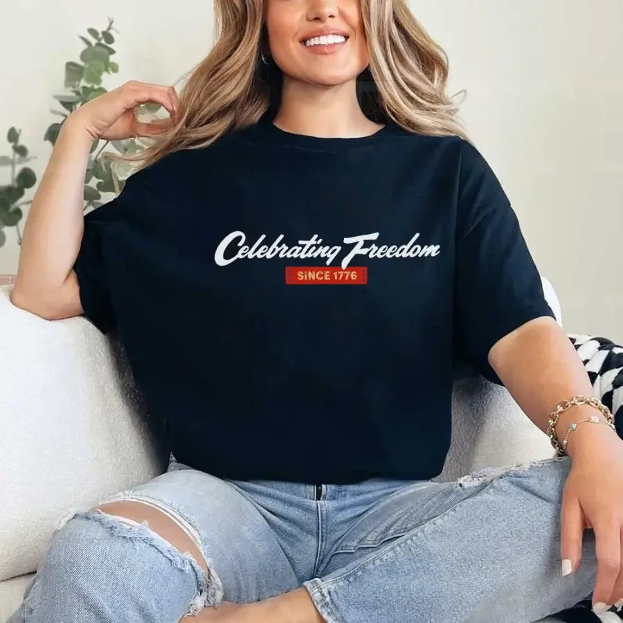 Person wearing a black t-shirt with 'Celebrating Freedom Since 1776' text, sitting on a couch.