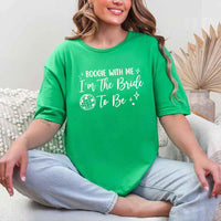 May include an Irish Green retro-style graphic tee with bold disco lettering reading “Boogie With Me, I’m The Bride To Be,” featuring playful fonts and festive design elements!