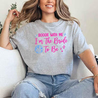 May include a Sport Grey retro-style graphic tee with bold disco lettering reading “Boogie With Me, I’m The Bride To Be,” featuring playful fonts and festive design elements!