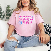 May include a Pink retro-style graphic tee with bold disco lettering reading “Boogie With Me, I’m The Bride To Be,” featuring playful fonts and festive design elements!