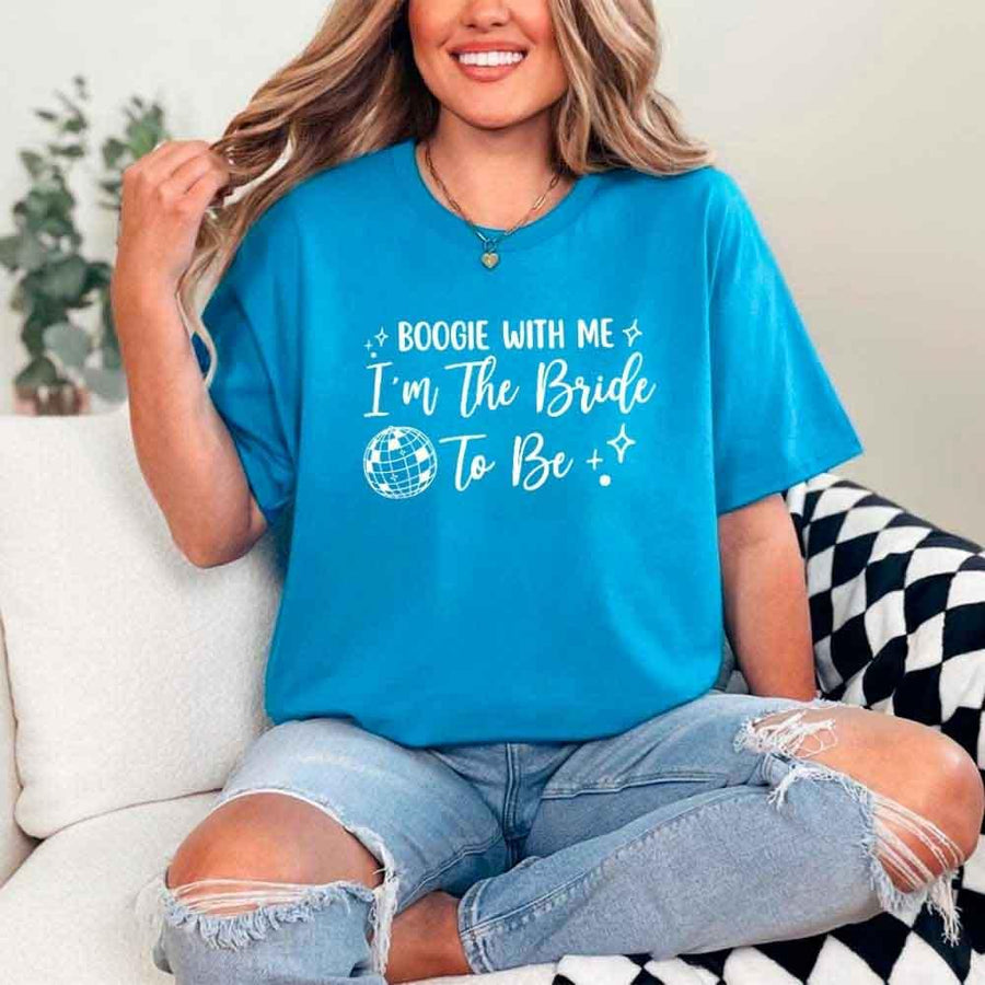 May include a Sapphire retro-style graphic tee with bold disco lettering reading “Boogie With Me, I’m The Bride To Be,” featuring playful fonts and festive design elements!