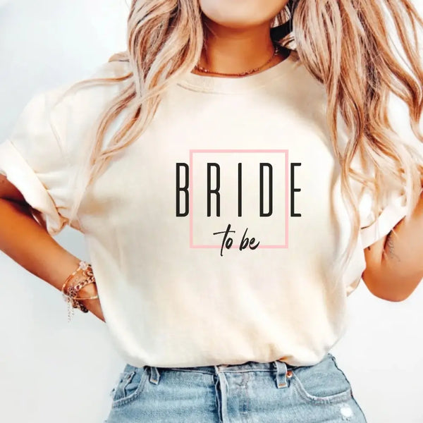 Woman wearing a white t-shirt with 'BRIDE to be' text on a plain background